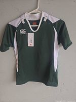 Front view of forest green and white Canterbury rugby jersey on hanger showing overall design