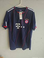 Front view of navy FC Bayern Munich jersey on hanger showing sponsor logo
