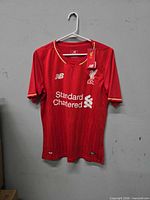 Full front view of red Liverpool jersey on hanger showing overall condition and tags attached