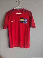 Front view of red England Nike soccer jersey on hanger