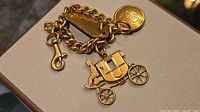 Full view of gold-tone Coach charm bracelet with carriage charm and tags