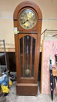 Front view of oak grandfather clock showing dial, glass door, and base