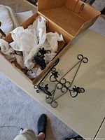 Box containing multiple black wrought iron wall sconces plus one displayed on table