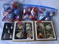Group shot of all ornament sets: two boxed Kurt Adler glass sets, boxed snowmen, two bags of foam disc ornaments