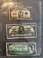 Three vintage Canadian banknotes held in plastic sleeve: 25 ¢, $20, $1