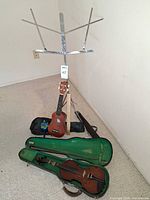 Violin in open case, bow, soprano ukulele with gig bag, music stand