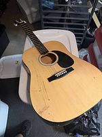 Full body of acoustic guitar showing natural finish and pickguard