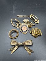 All seven brooches arranged on black surface