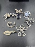 Group shot of all seven silver-tone brooches