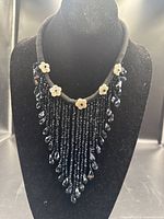 Full view of black glass fringe bib necklace on display bust