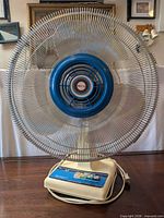 Front view showing entire fan with metal grill and blue hub
