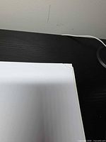 Corner of white background sheet on black table