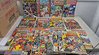 Overview of entire lot showing more than twenty Captain Marvel and Marvel Spotlight comics spread on table.