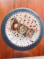 Top view of handcrafted pottery bowl showing polka dot and abstract motif interior with black rim
