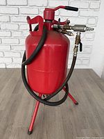 Full view of red sandblast tank with hose, fittings, stand and handle