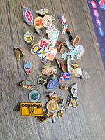 Full group of assorted enamel lapel pins spread on table