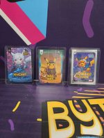 Group shot of three trading cards in stands: Warcraft, Mad Max, Howard the Duck variants