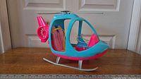 Side profile of pink and blue Barbie Travel Helicopter showing rotors and skids