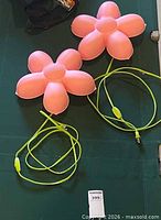 Overview of two pink flower wall lamps with yellow-green cords