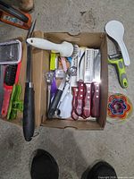 Overview of box showing Tramontina knives, peeler, rice paddle, graters, measuring spoons and cookie cutters