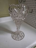 Full view of clear cut glass vase on pedestal foot