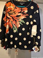Front of navy polka-dot floral top on hanger