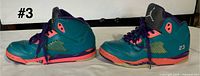 Left and right lateral view of both sneakers showing teal uppers, pink midsoles, purple lace area, stitched 23 and general wear