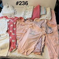 Full lot showing stacks of bibs and blankets with clothing pieces laid out