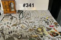 Overview of entire lot on table with jewelry box, necklaces, bracelets, earrings, watches