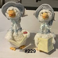 Two white plush Mother Goose figures with glasses, blue bonnets and books, tags visible