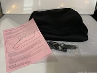 folded black mesh heated seat cover, power cord, pink user guide sheet