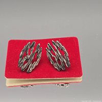 Front view of both cufflinks on red backing showing abstract design