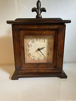 Front view showing dial, wood case and finial