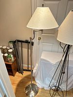 Silver brushed nickel floor lamp with fabric shade beside jars