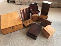 Group of various wooden boxes with different wood finishes and sizes arranged on carpeted floor.