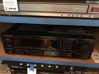 Front view of Pioneer VSX-5600 stereo receiver on shelf with remote control on top, accompanied by label indicating 2 pieces.