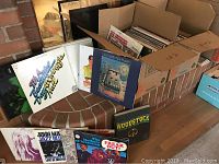 Two boxes full of LP records featuring various artists and one preview of album covers.