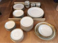Complete set of plates, bowls, cups and saucers arranged on floor showing quantity and style.