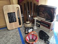 Full view of the kitchen tools set showing cheese cutting board, knives on hanging board, sharpener, torch, herb holder etc.