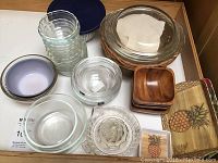 Top-down view of various glass Pyrex bowls, wooden bowls, trays, and casserole.