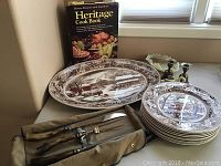Overview of the Johnson Bros oval platter, matching dinner plates, meat carving set, candle holders, swan piece, and Heritage Cookbook