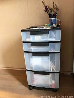 Full view of 4-drawer storage bin with paint brushes in mug on top