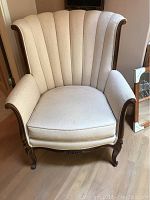 Frontal view of vintage wing back chair showing scalloped vertical channel upholstery and wooden frame