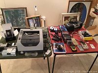 Overview of Brother HL 5340D laser printer, multiple electronic devices including phones, radios, and cassette player on tables