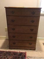Front view of the chest showing five drawers with brass-style handles and smooth wood finish.