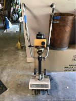 Front view of the IDC rototiller showing handles, motor and wheels.