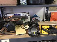 Jet scroll saw with white metal frame and blue logo, showing motor and band saw blades on table.