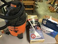 Photo of the Shop-Vac wet/dry vacuum with attached hose alongside boxed Steam Team cleaning attachment and unopened Steam Fast Hot & Handy steam cleaner box.