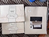 Three factory-sealed bedding packages: two Bed Bath & Beyond king flat sheets and one Hotel Collection blanket