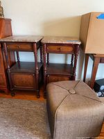 Pair of marble-top nightstands beside cube ottoman
